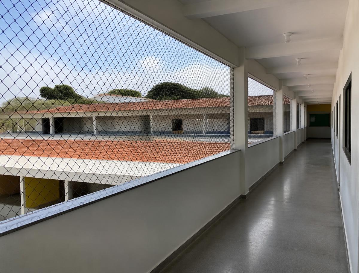 Corredor elevado de escola com rede de proteção instalada no vão